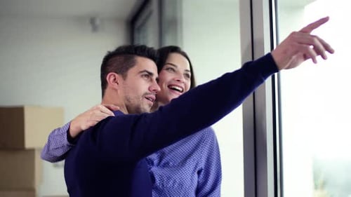 Couple With Cardboard Boxes Moving In A New Home, Hugging. Copy Space.