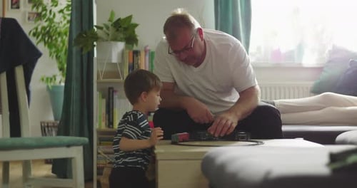 Father and Son Play with Toy Train Set Indoors