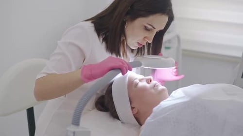 Cosmetologist Examining Woman's Face with Magnifying Glass