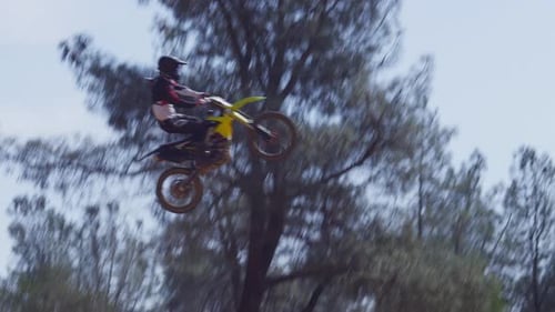 Person on dirt bike jumps high over ramp