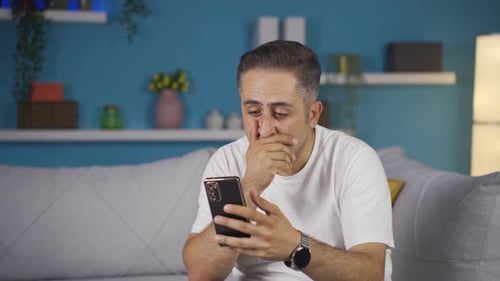 Man Looks Frustrated While Using Cellphone At Home
