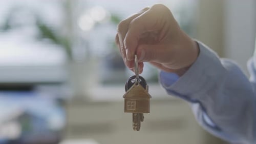 Hand of Real Estate Agent Holding House Keys in Office