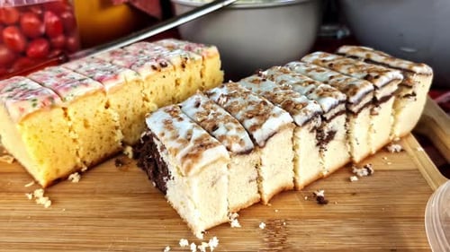 Sliced iced sponge cakes on wooden tray at buffet