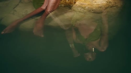 Reflection of Androgynous Black Lgbtq Fashion Model Lies on Stones Inside Picturesque Natural Pool