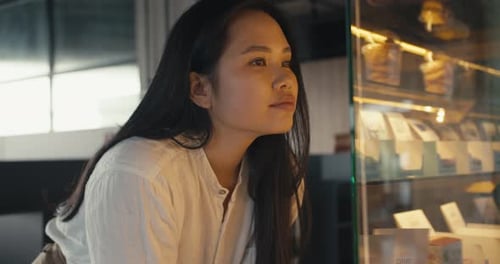 Woman Looks at Dessert Case in Cafe