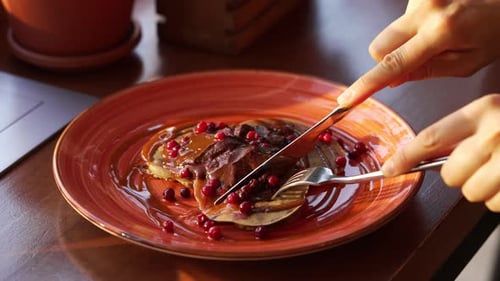 Hands Cutting Pancakes with Knife and Fork Close Up