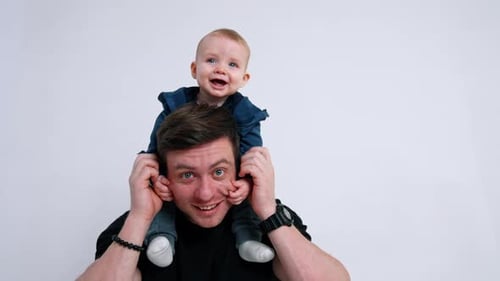 Happy Father with Baby Son on Shoulders Smiling