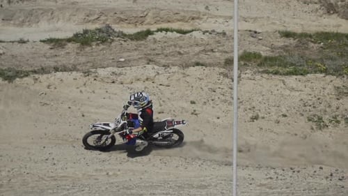Motocross rider takes turn on dirt track in slow motion.