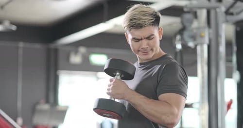 Deportista haciendo ejercicios con mancuernas, hombre fuerte que se mantiene en forma en el gimnasio.