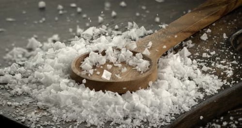 White salt crystals fall out in slow motion.