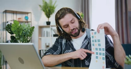 Likable confident man in headset explaining financial report with statistics during video conference