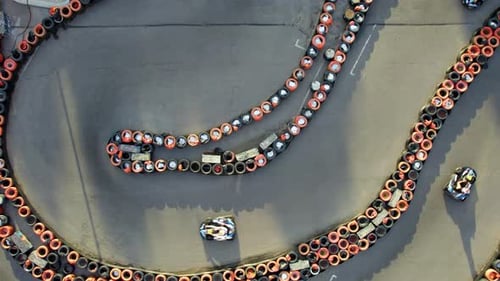 Aerial top view of the go-kart track from the drone. Kart racers drive on the open track.