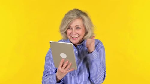 Mature Woman Using Tablet, Happy Reaction on Yellow