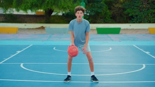 Teen Boy Dribbling Basketball on Outdoor Court