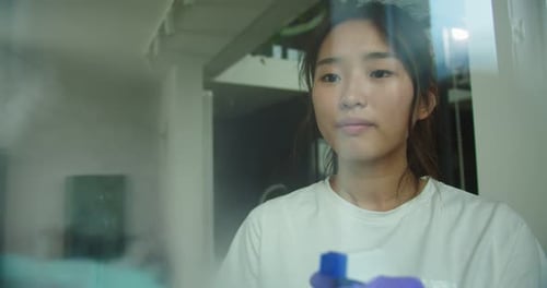 Close Up of Asian Woman Washing Glass with Sponge Happy Female in Gloves Cleaning Window By Spraying