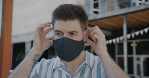 Man Puts on Protective Face Mask in City