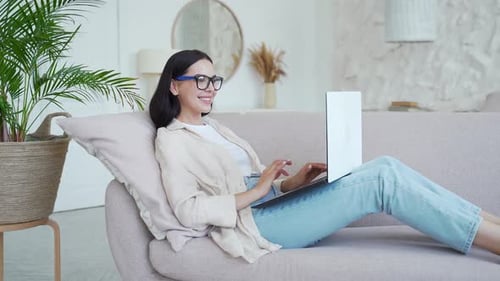 Woman Using Laptop on Sofa in Home