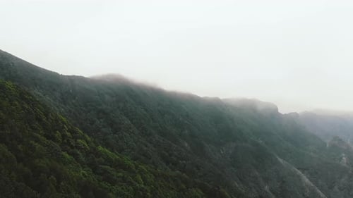 Flight in the clouds in mountains, morning clouds in the mountains aerial. Aerial view above the clo