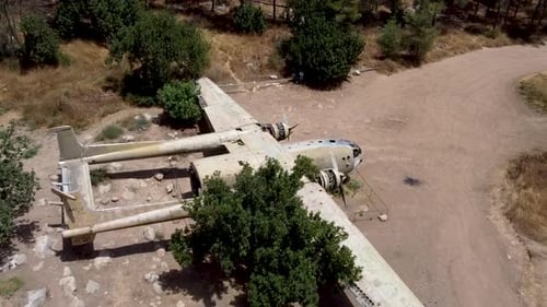 Aerial slow forward, zoom in drone shot of an old dismantled army plane monument placed on an empty