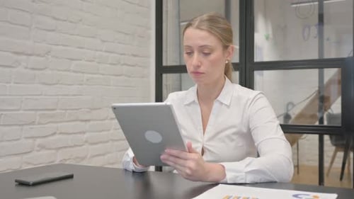 Mature Business Woman Celebrating Success on Tablet in Office