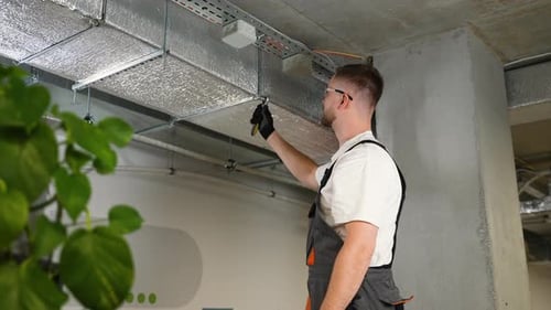 Professional Installer Tightening a Bolt on a Ventilation Duct