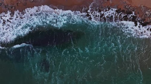 Waves crashing on a rocky beach shoreline in daylight hours