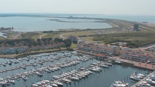 Cinematic drone / aerial tracking panorama shot of a marina / port with sailing boats on a sunny day