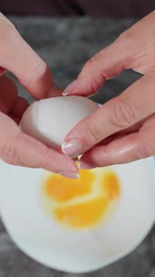 Luftaufnahme des Küchenchefs, der auf der Küchentheke in eine Schüssel mit Zucker in der Nähe ein Ei knackt