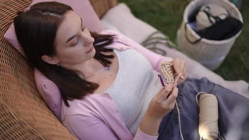 Woman Crocheting While Relaxing on Lounge Chair