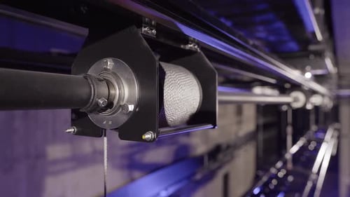 Metal Cable Rolls Out from a Hoist Spool. Stage Truss in the Background.