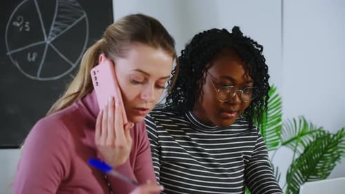Women Collaborate in Office, Talking on Phone