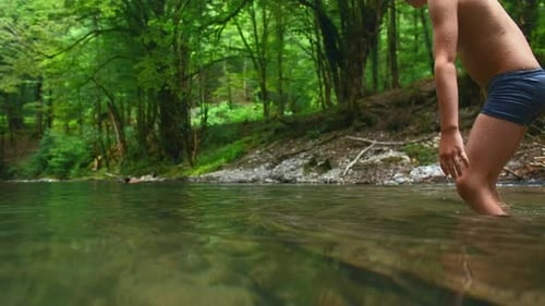Um menino tomando banho em uma piscina de rio na montanha. Criativo. Criança se divertindo em um lago natural de verão.