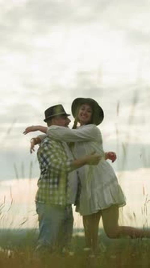 Romantic Couple Embracing in a Scenic Grass Field at Sunset