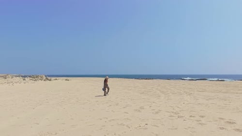 Aerial View of a Young Woman Walking Across a Wide Sandy Beach Along the Coast of Cal Madow Somalia