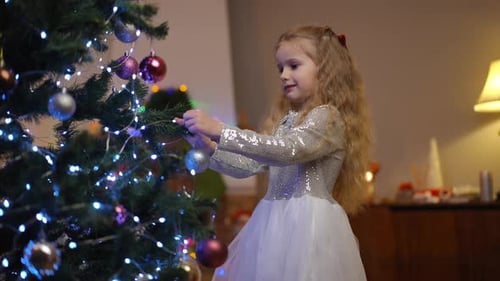 Girl Decorates Christmas Tree with Bauble Ornament