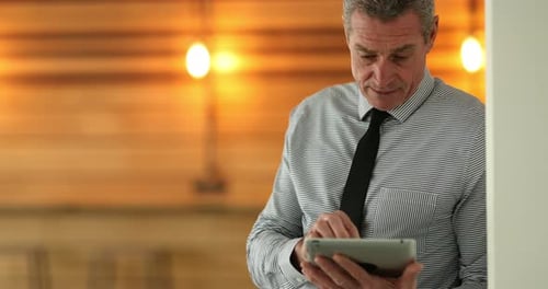 Focused Mature Businessman Standing in the Hallway of a Modern Office Working