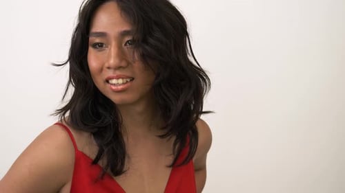 Joyful transgender woman with wavy hair smiles in a studio portrait session