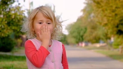 Child Blowing Kiss on Street Selective Focus