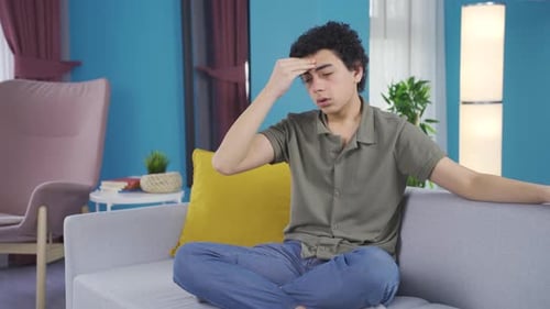 Young Adult Experiencing Headache Indoors on Sofa