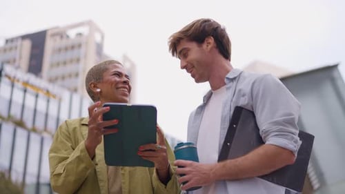 Woman Showing Tablet to Man Outside Urban Building