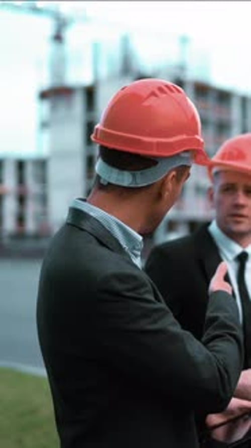 Vertical of Construction Worker and Businessmen Talking on Site
