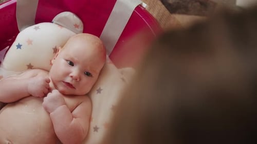 Mother Bathes Her Baby in Pink Bathtub Top View