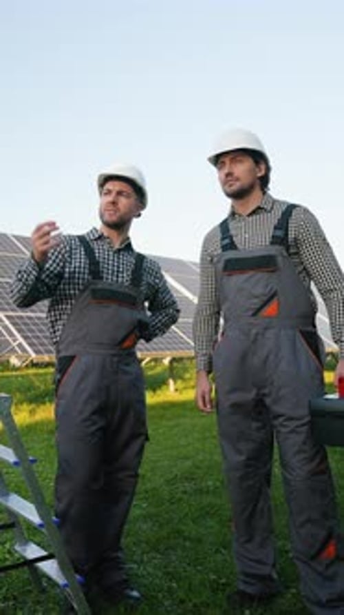Workers Discussing Solar Panel Installation with Tools