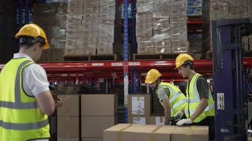 Blue collar workers are working at warehouse.