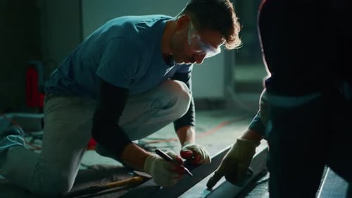 Trabajador de cerca midiendo, marcando el diseño de mosaicos con lápiz y cuadrado, iluminación enfocada en el interior del sitio