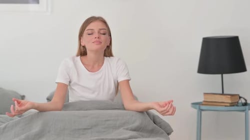 Young Woman Meditating in Bed for Relaxation