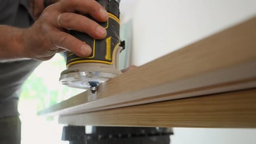 Man's Hands Rout Wood with Power Tool Indoors
