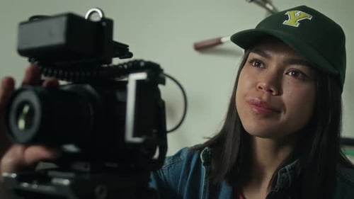 Young Woman Adjusting Professional Camera on Tripod