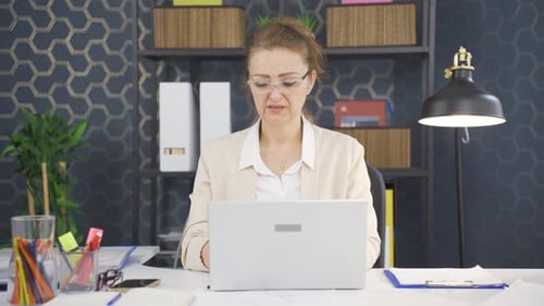 Geschäftsfrau schaut müde von der Arbeit in die Kamera.