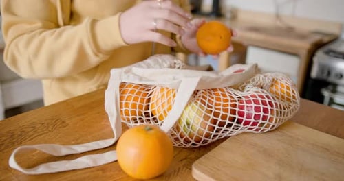 Estudiante desempacando fruta orgánica de una bolsa de compras reutilizable